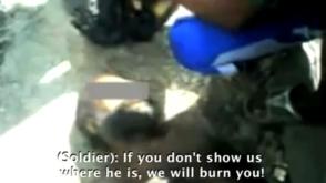 Een Papoea-man ligt vastgebonden op de grond als militairen hem 
ondervragen