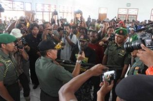 Former OPM leader Daniel Kogoya (center) turning over his weapon to law enforcement authorities in Jayapura on Friday. Behind him are more than 200 rebels under his command who police say have all surrendered as well. (JG Photo/Banjir Ambarita)